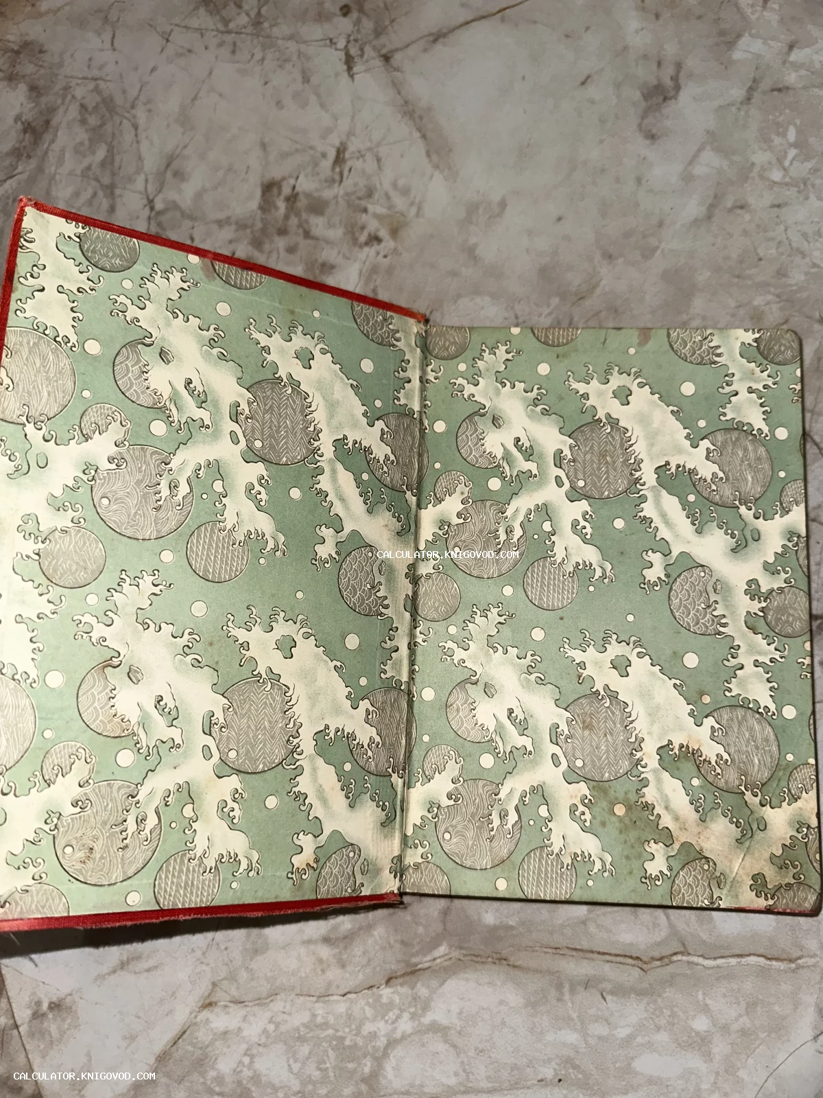 Разворот старинной книги с узорчатым форзацем, изображающим стилизованные морские волны и круги в пастельных тонах.