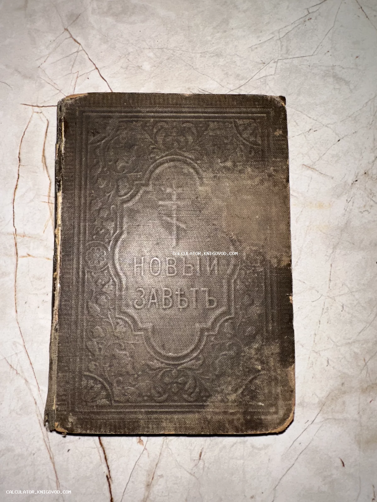 Обложка старинной религиозной книги «Новый Заветъ» с тиснением и православным крестом.