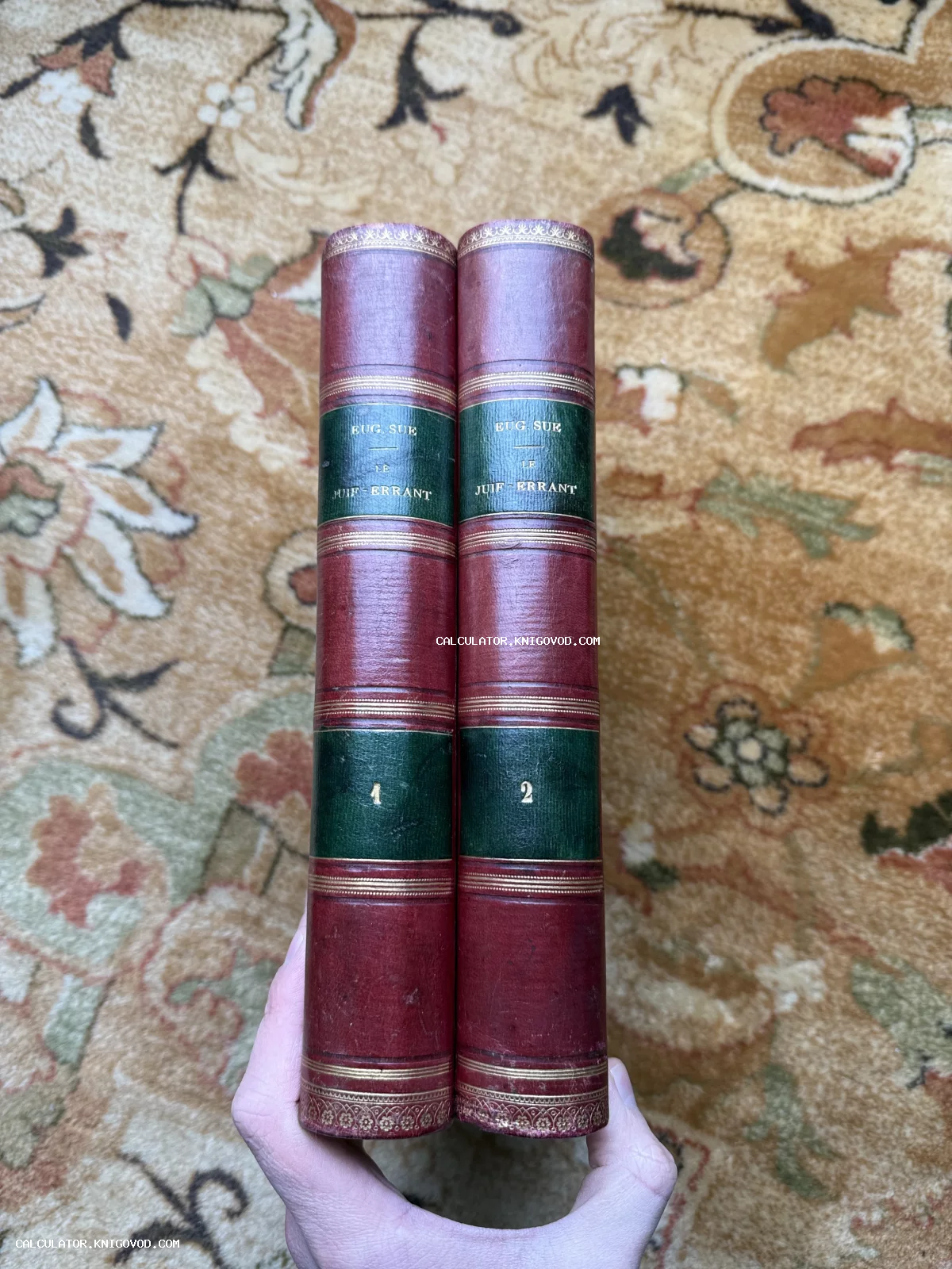 Два тома антикварной книги Эжена Сю 'Вечный жид' с красными корешками и золотым тиснением.