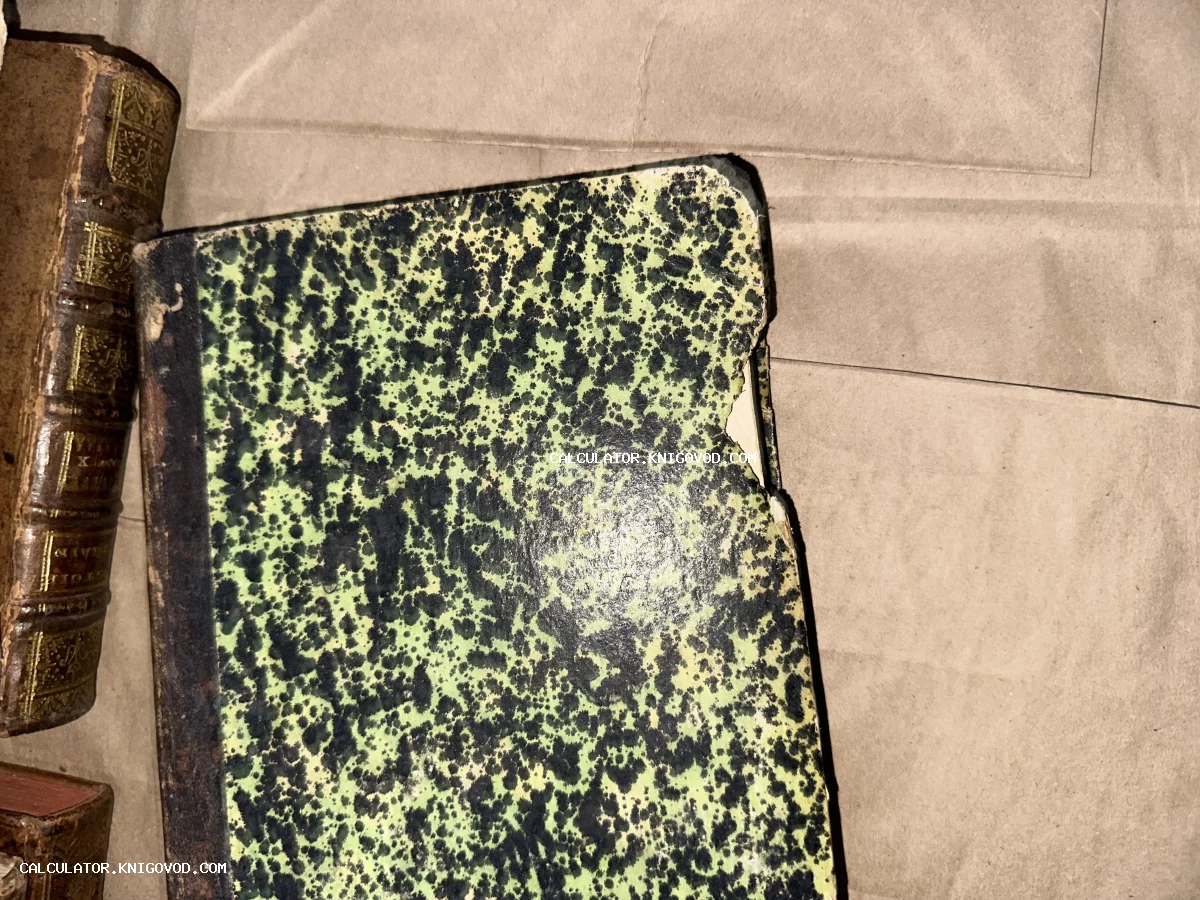 Крупный план обложки антикварной книги с зелено-черным мраморным узором и кожаным корешком с золотым тиснением.