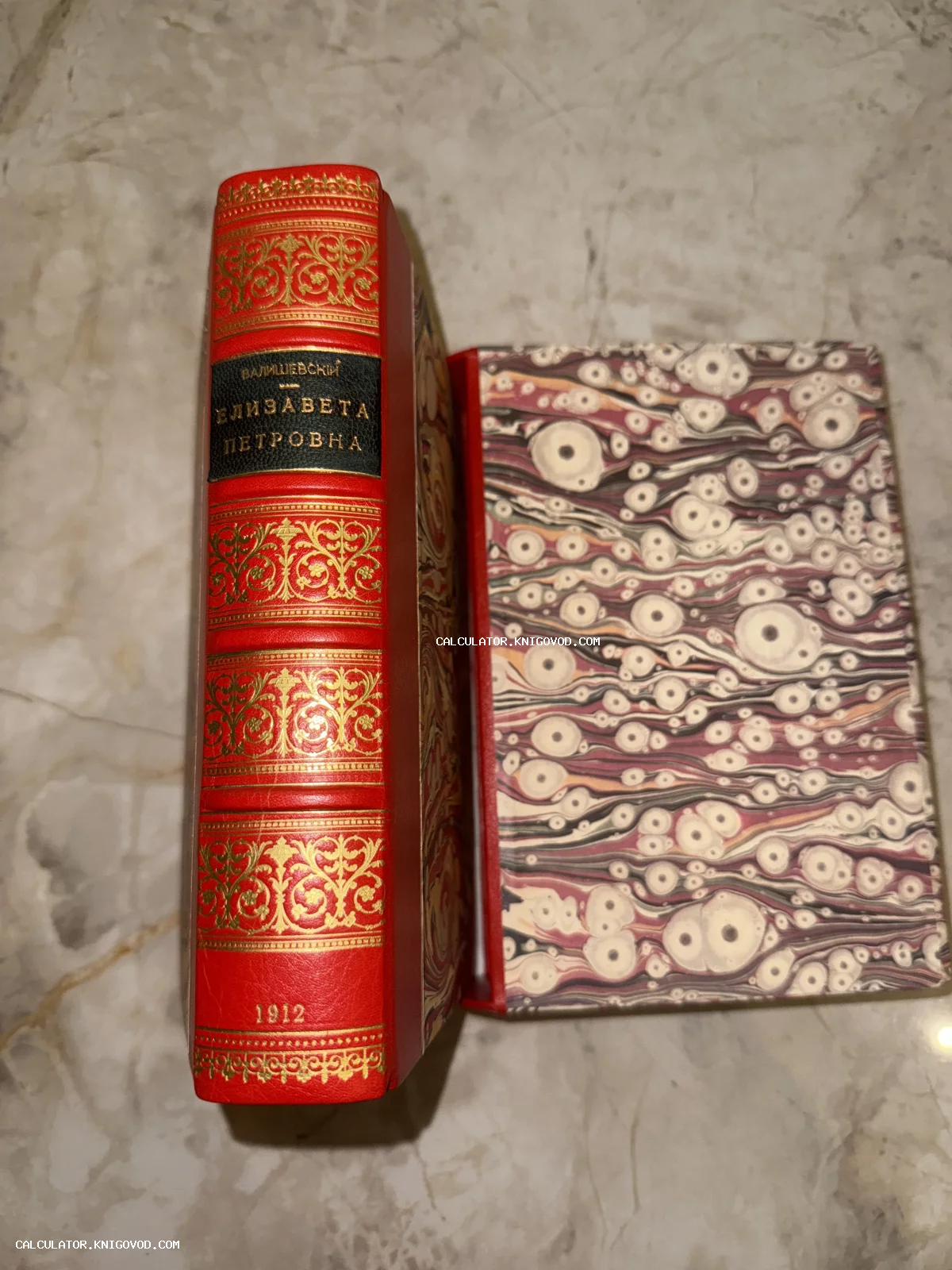 Корешок антикварной книги из красной кожи с золотым тиснением и обложка с мраморным рисунком.