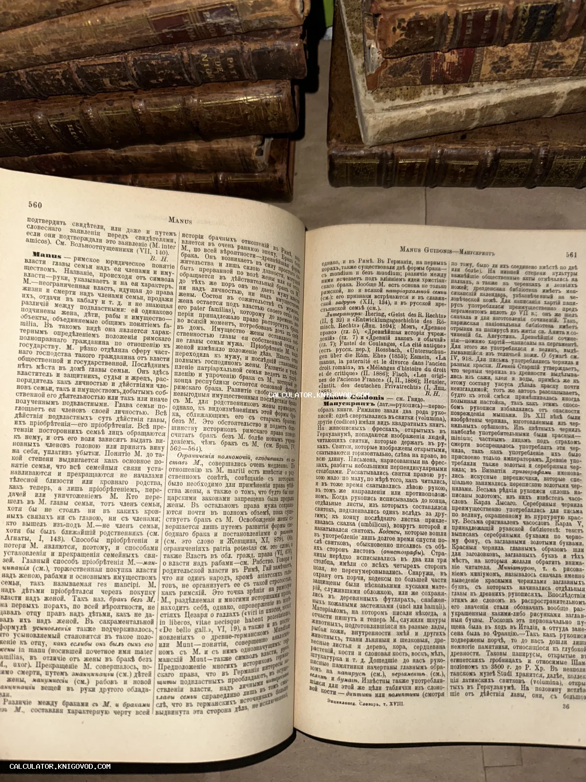 Развернутая старинная книга с текстом на дореволюционном русском языке, лежащая на стопке книг в темных кожаных переплетах.