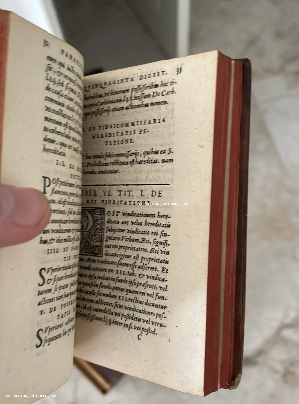 Разворот старинной книги с латинским текстом, красным обрезом страниц и декоративной буквицей.