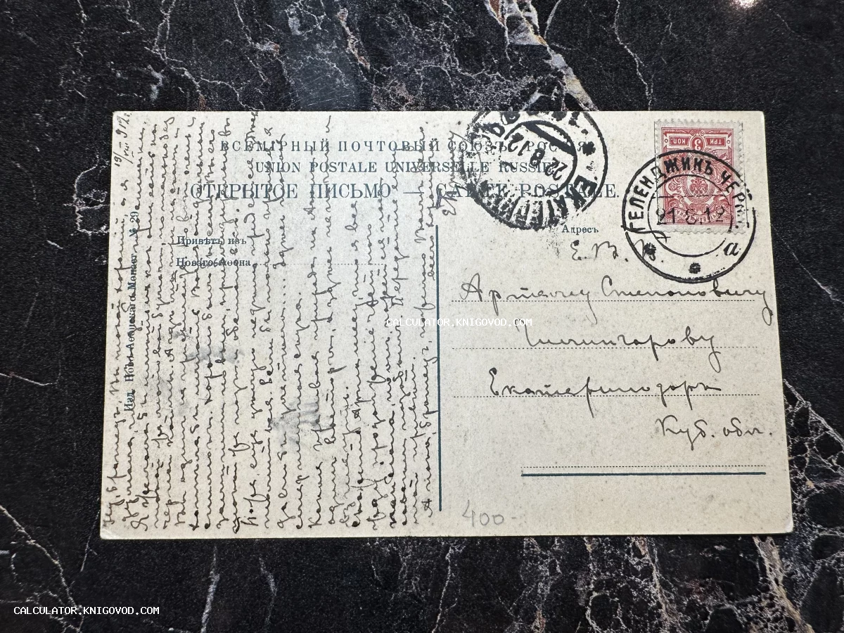 Оборотная сторона антикварной почтовой карточки с рукописным текстом, почтовой маркой и штемпелями города Геленджик.