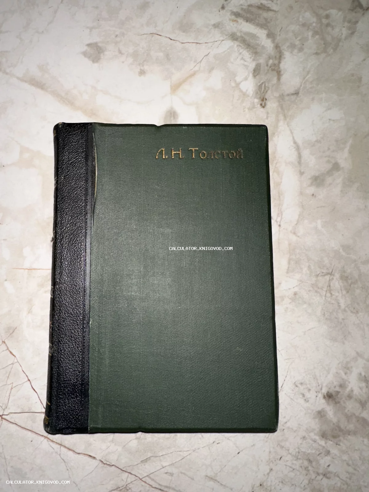 Старинная книга Л. Н. Толстого в темно-зеленом тканевом переплете с золотым тиснением и черным корешком.