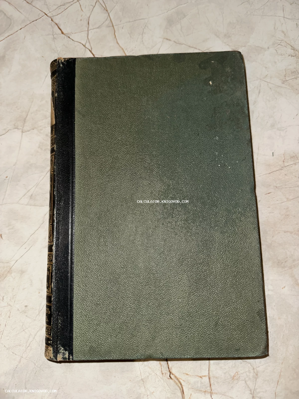 Старинная книга с темно-зеленой фактурной обложкой и черным корешком с золотым тиснением на светлом фоне.