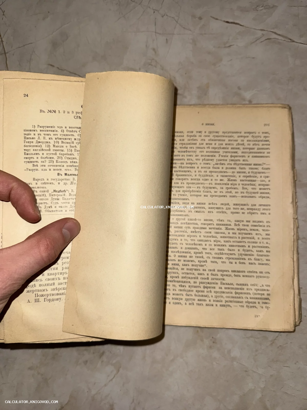 Разворот старинной книги на русском языке с дореволюционной орфографией, мужская рука придерживает пожелтевшие страницы.