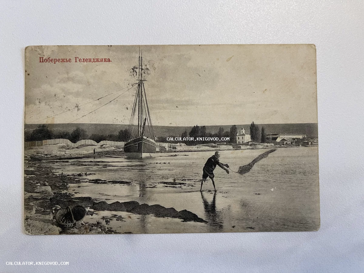 Антикварная черно-белая открытка с надписью «Побережье Геленджика», изображающая рыбака с сетью и парусное судно у берега.
