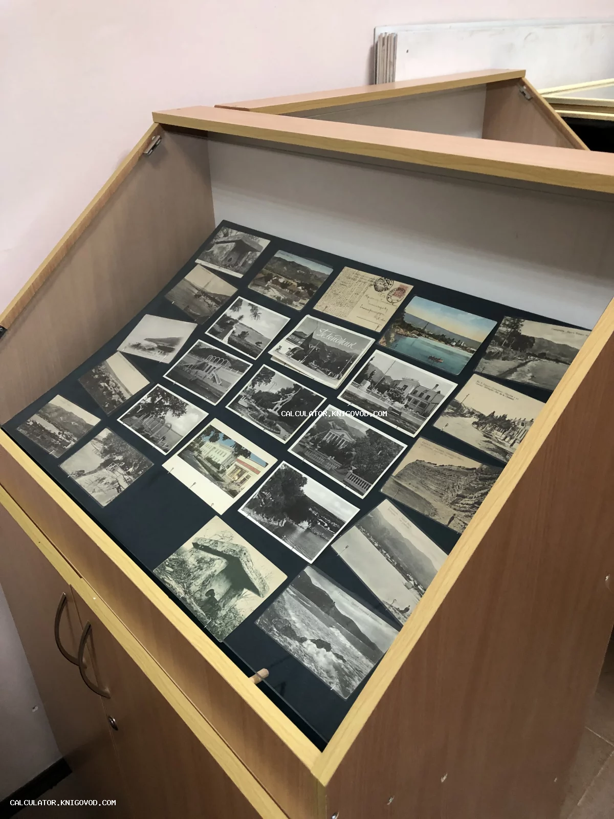 Экспозиция антикварных почтовых карточек начала XX века в деревянной музейной витрине.