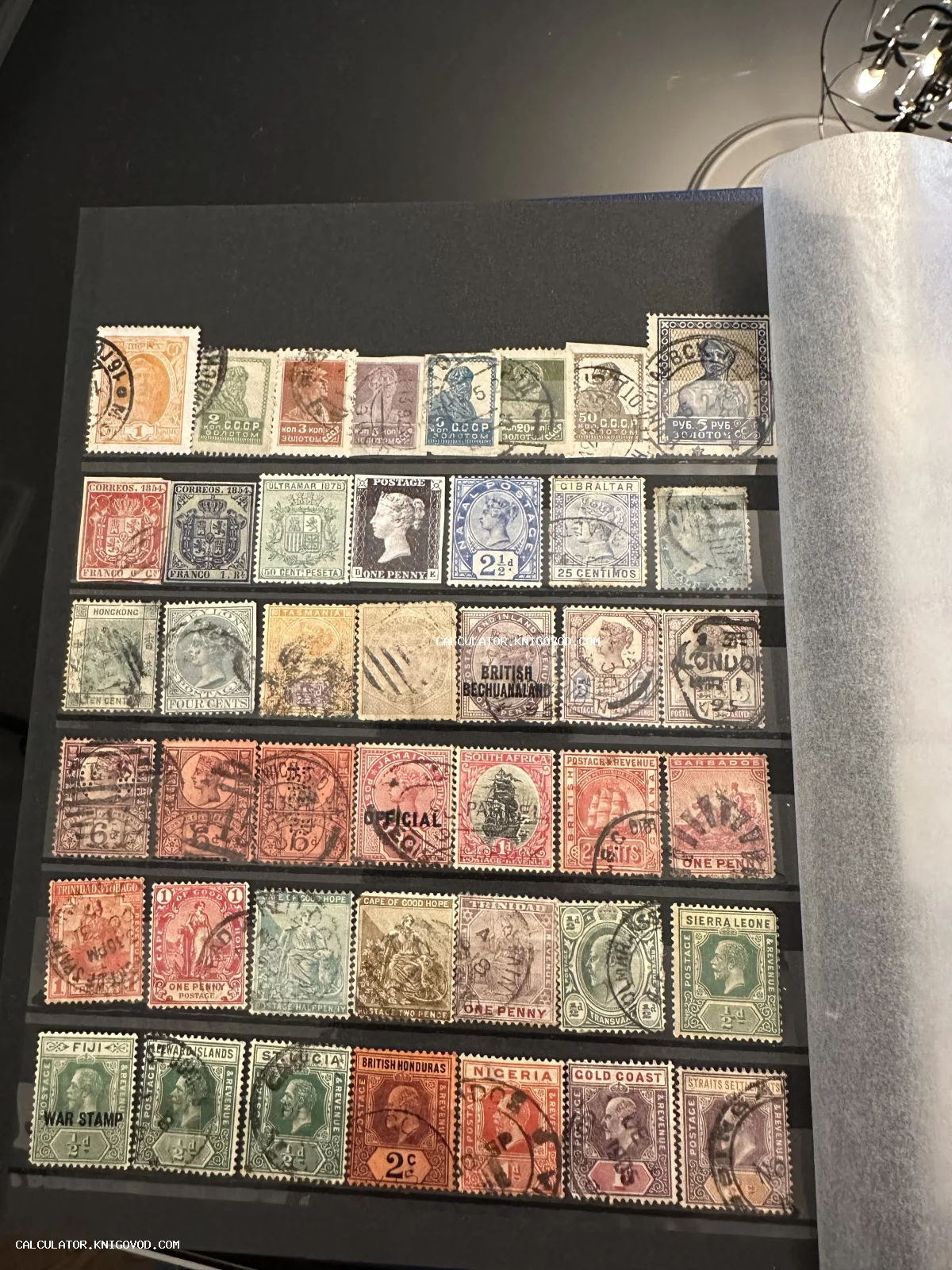 Страница кляссера с рядами старинных почтовых марок СССР и британских колоний с почтовыми штемпелями.