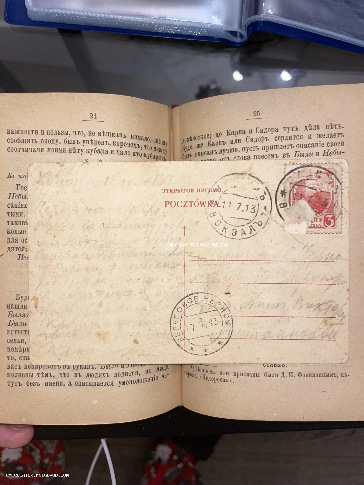 Антикварная почтовая карточка с марками и штемпелями 1913 года, лежащая на страницах открытой старой книги.