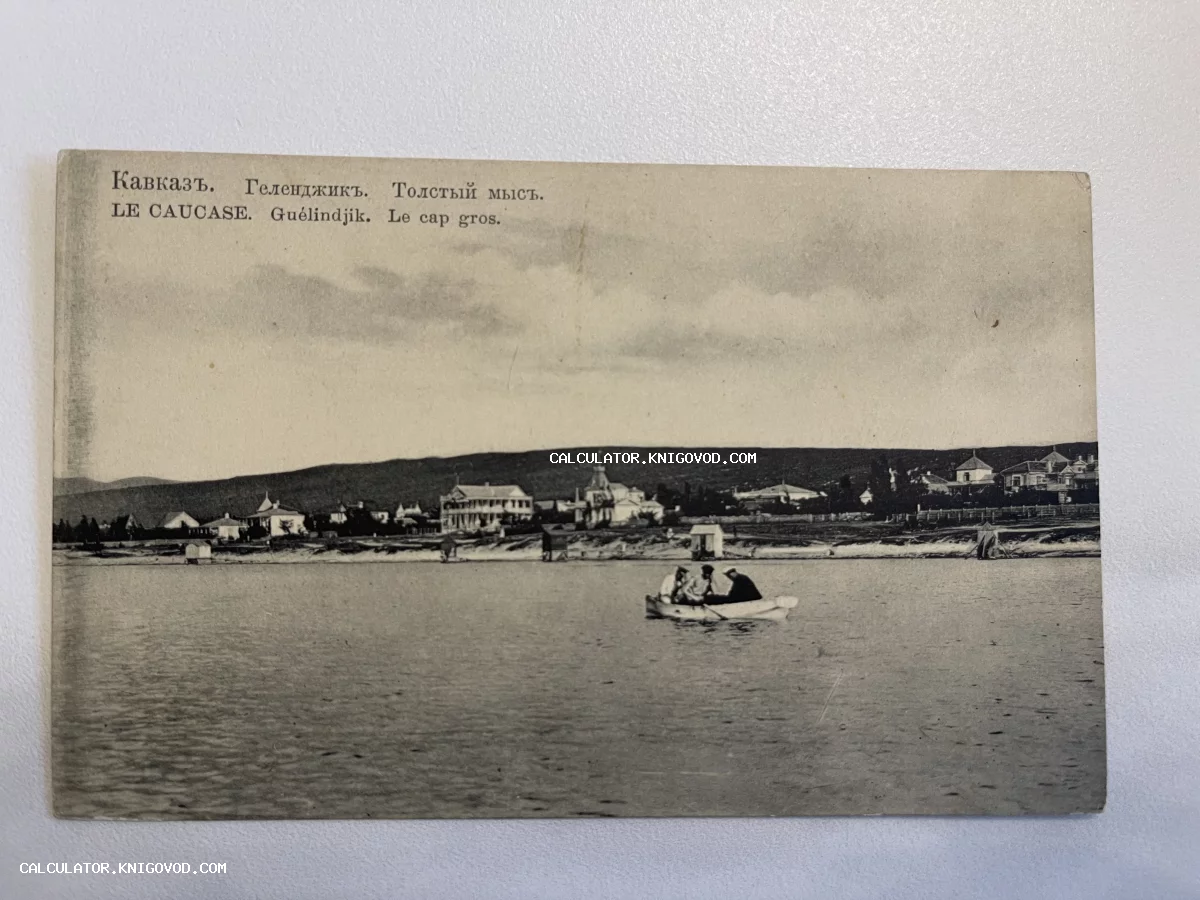 Черно-белая почтовая открытка начала XX века с панорамой Толстого мыса в Геленджике и лодкой на воде.