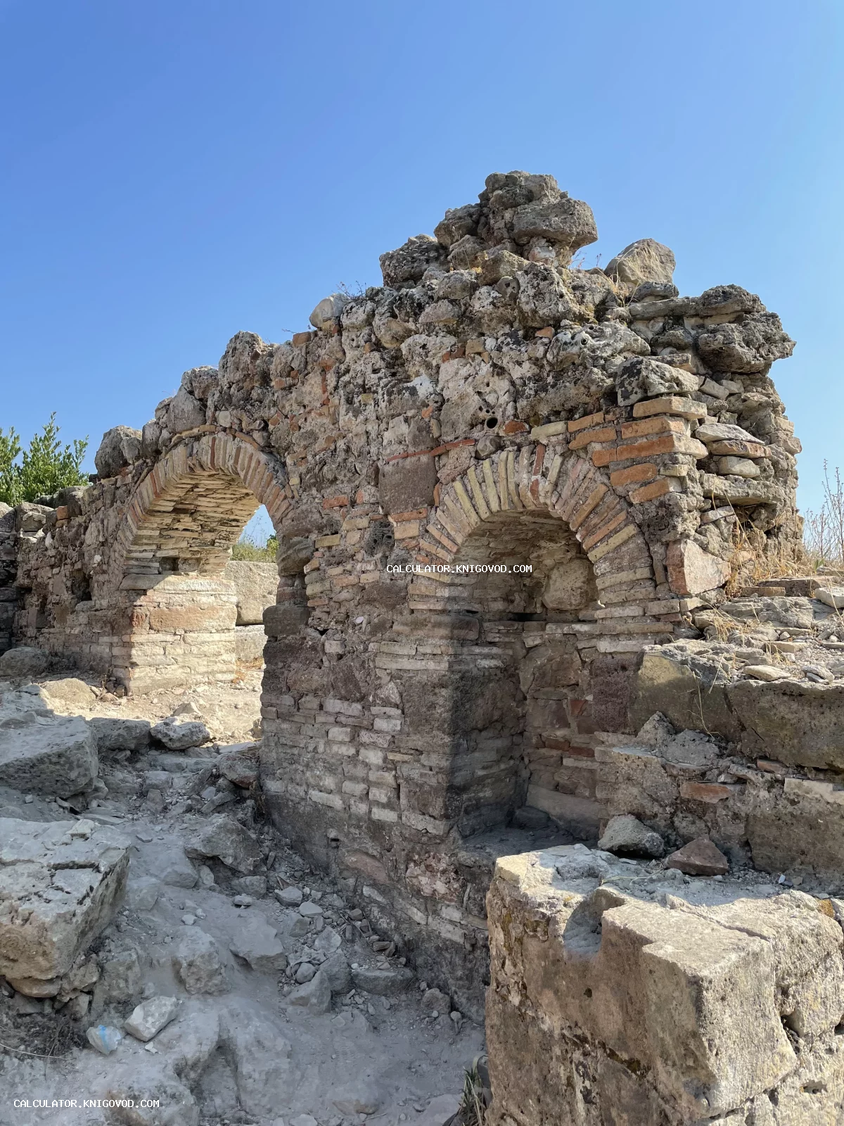 Руины древнего сооружения с сохранившимися кирпичными арками на фоне голубого неба.
