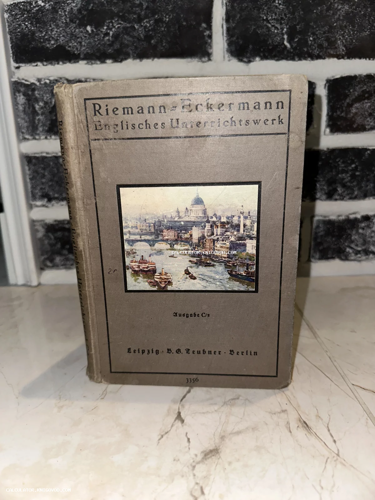 Старинная книга в сером тканевом переплете с цветной иллюстрацией Лондона на обложке.