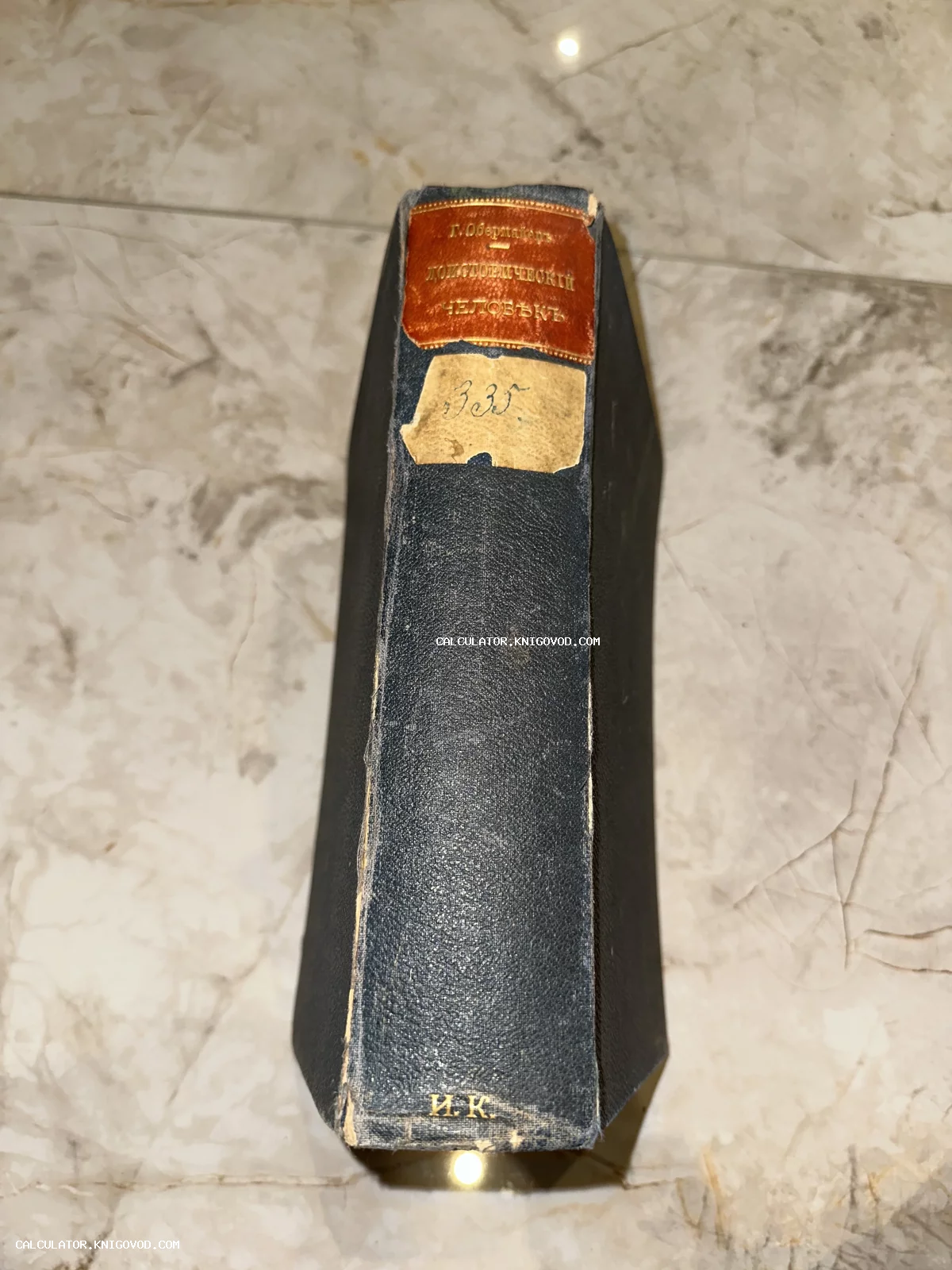 Корешок старинной книги Г. Обермайера под названием Доисторический человек с золотым тиснением и бумажным ярлыком.