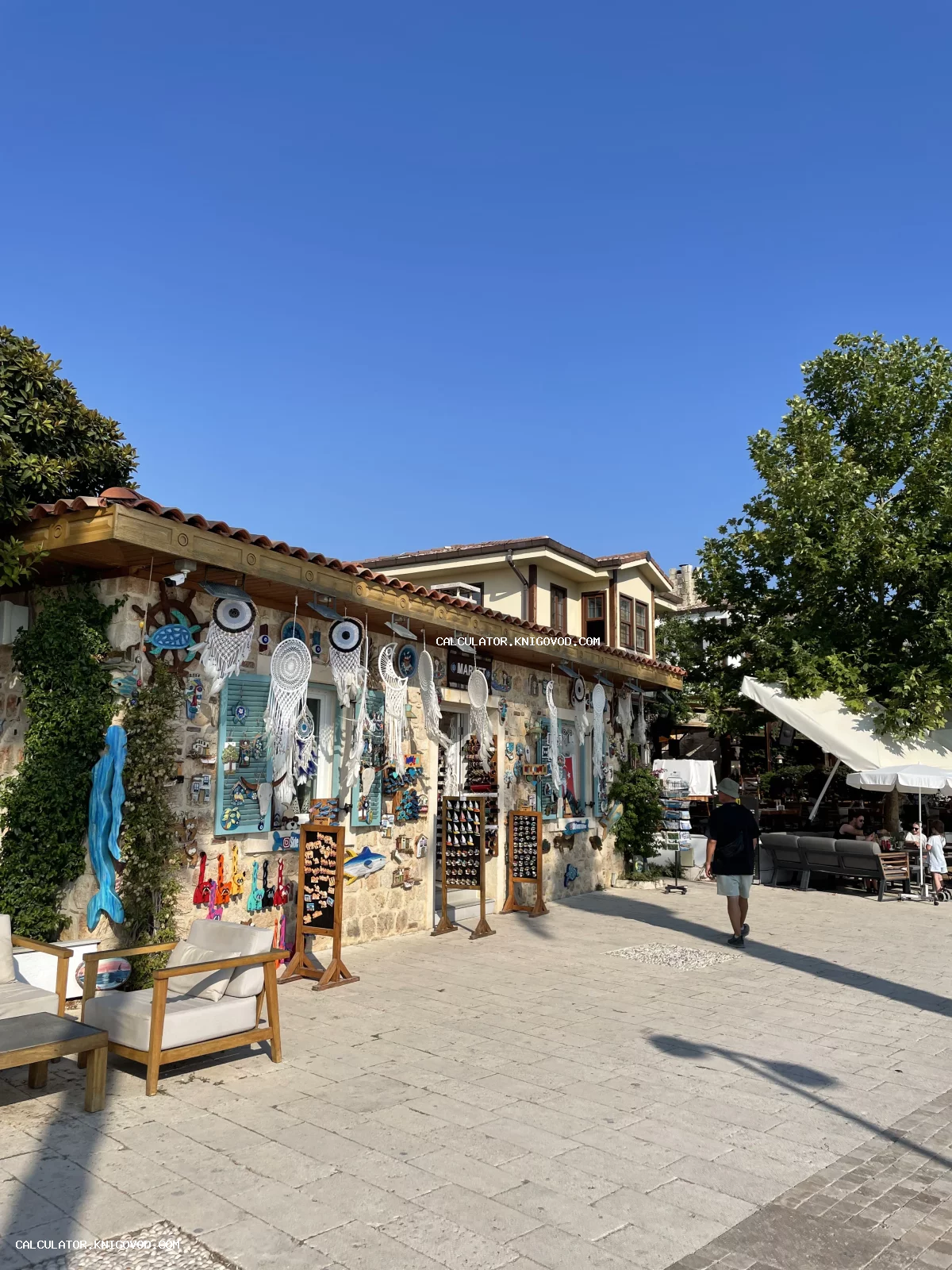 Каменное здание сувенирного магазина, украшенное многочисленными ловцами снов и турецкими оберегами на фоне голубого неба.