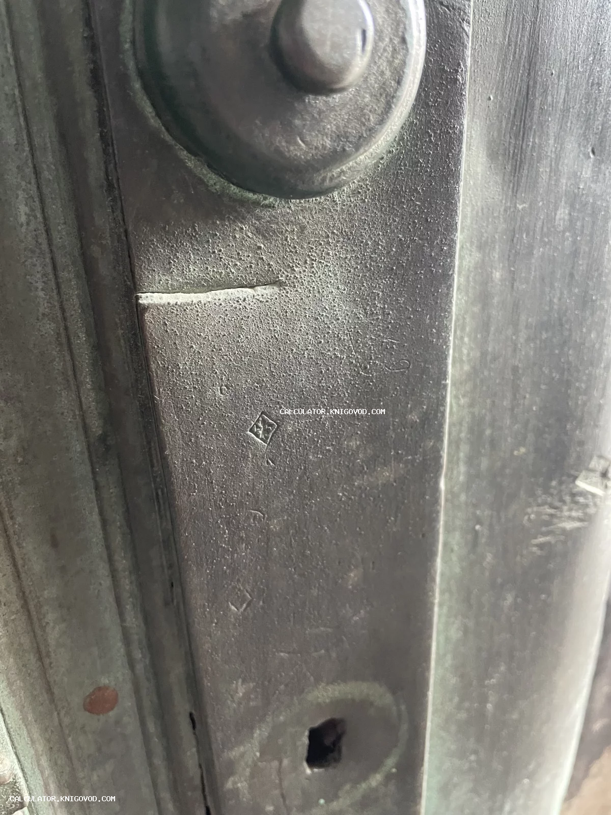 Крупный план старинного металлического изделия с густой патиной и четким ромбовидным клеймом мастера.