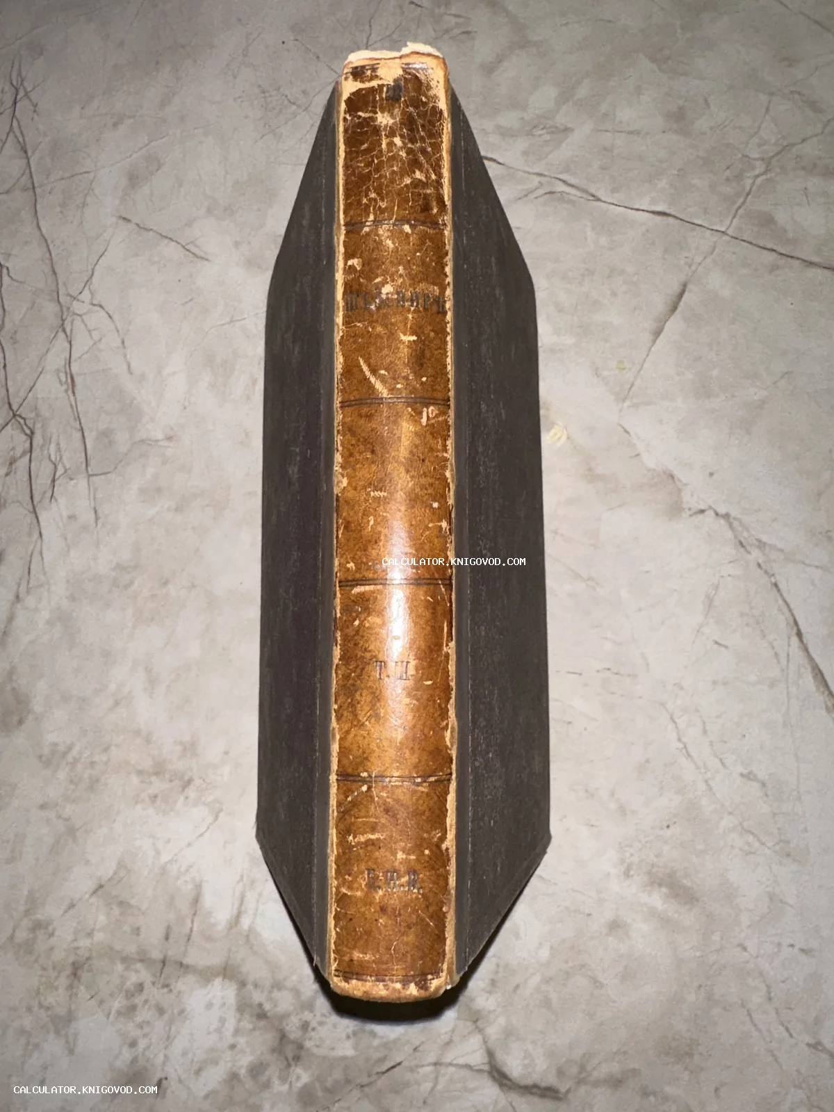 Корешок старинной книги с золотым тиснением «Шекспиръ», том третий, в полукожаном переплете на мраморной поверхности.