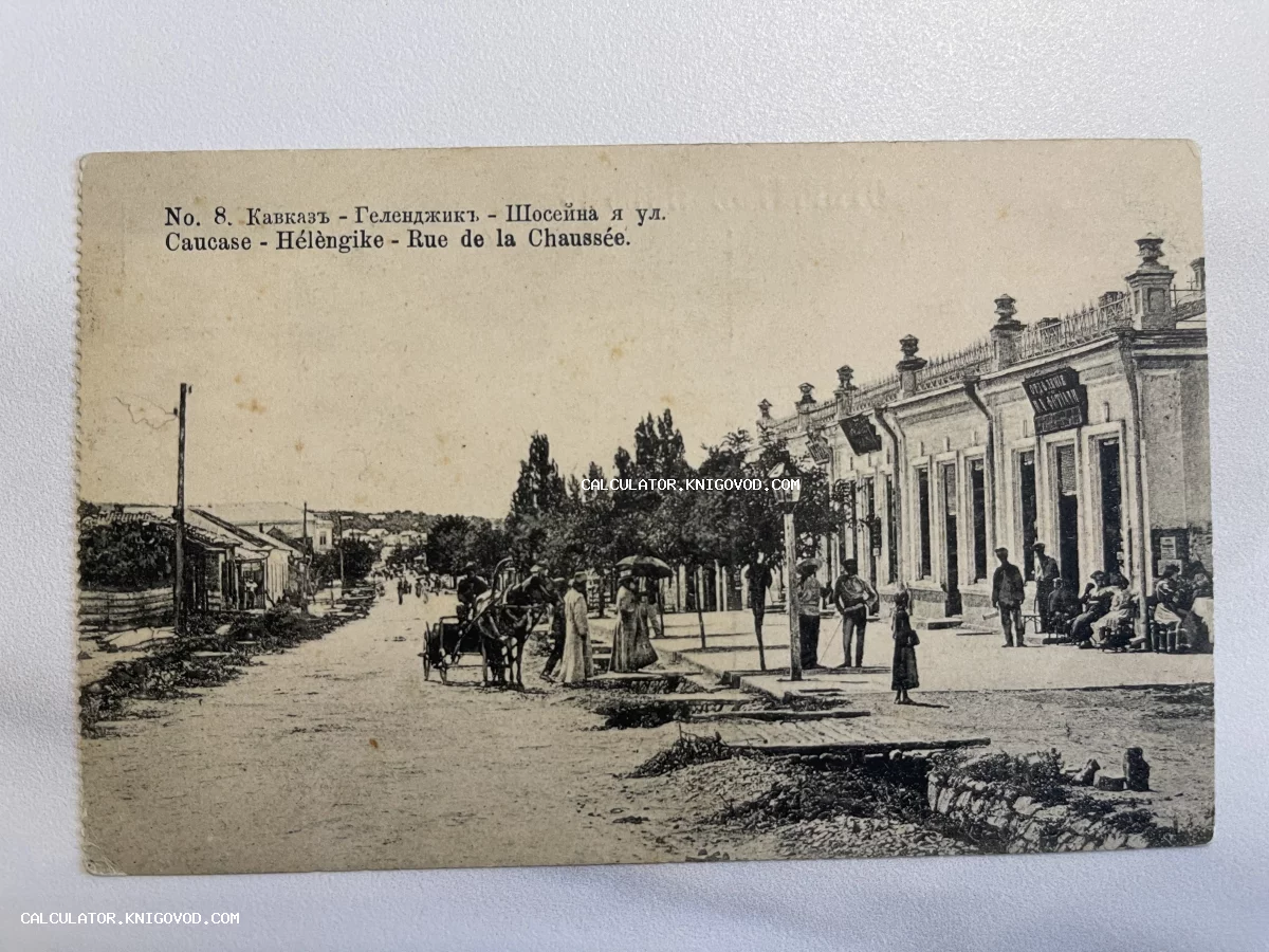 Старинная почтовая карточка с видом на Шоссейную улицу в Геленджике начала XX века, изображающая прохожих, повозку с лошадью и каменные здания.