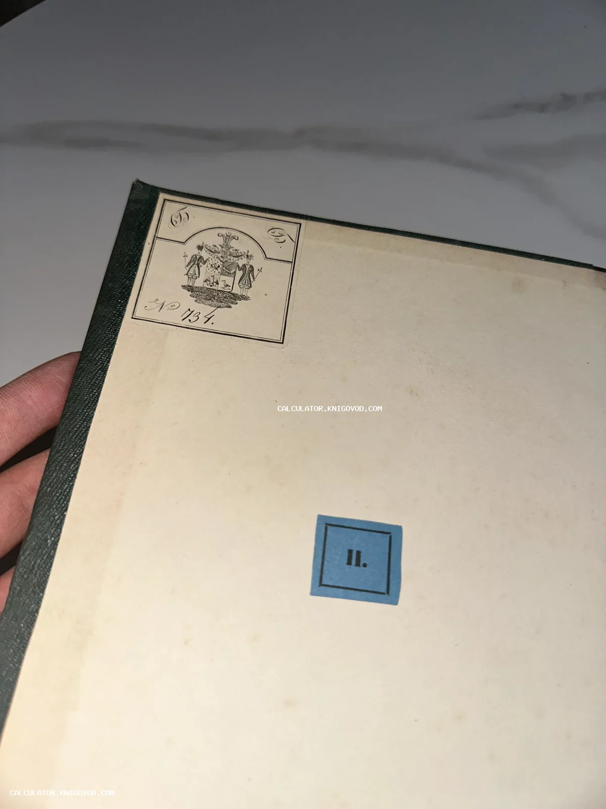 Форзац старинной книги в зеленом переплете с наклеенным гербовым экслибрисом и синей библиотечной меткой с цифрой II.