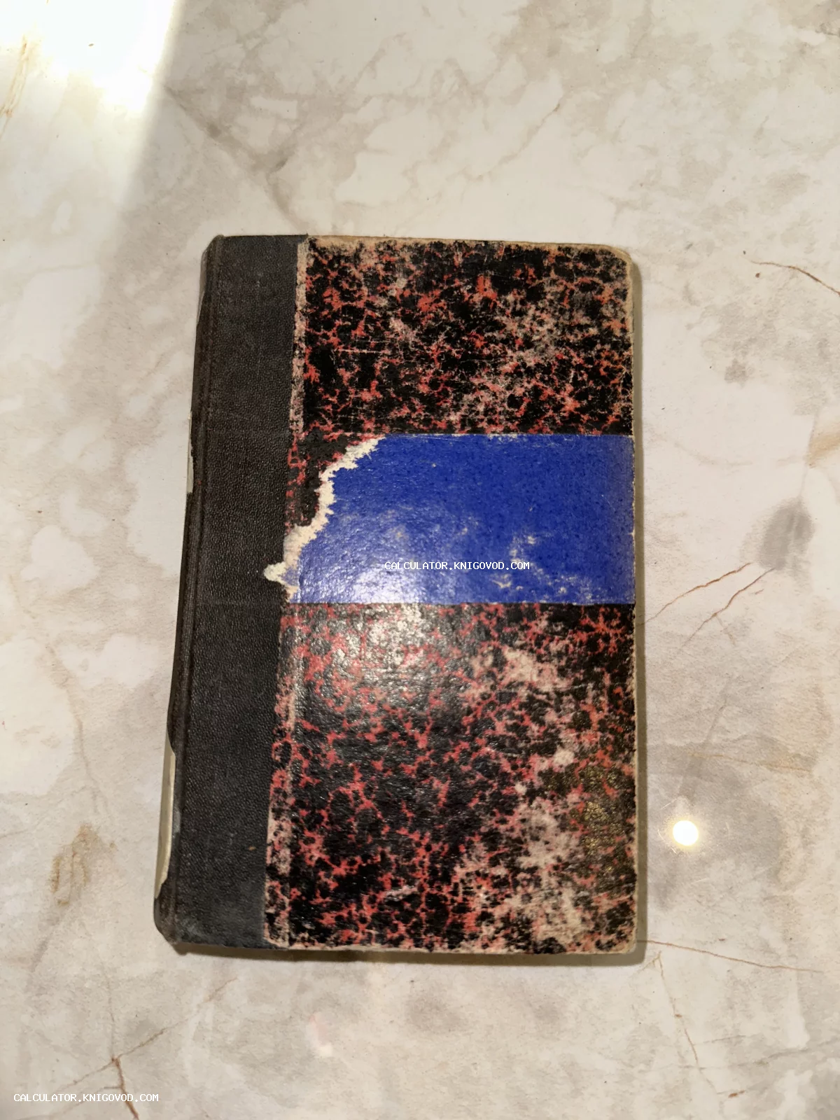 Старинный блокнот в твердом переплете с черно-красной мраморной обложкой и синей полосой.