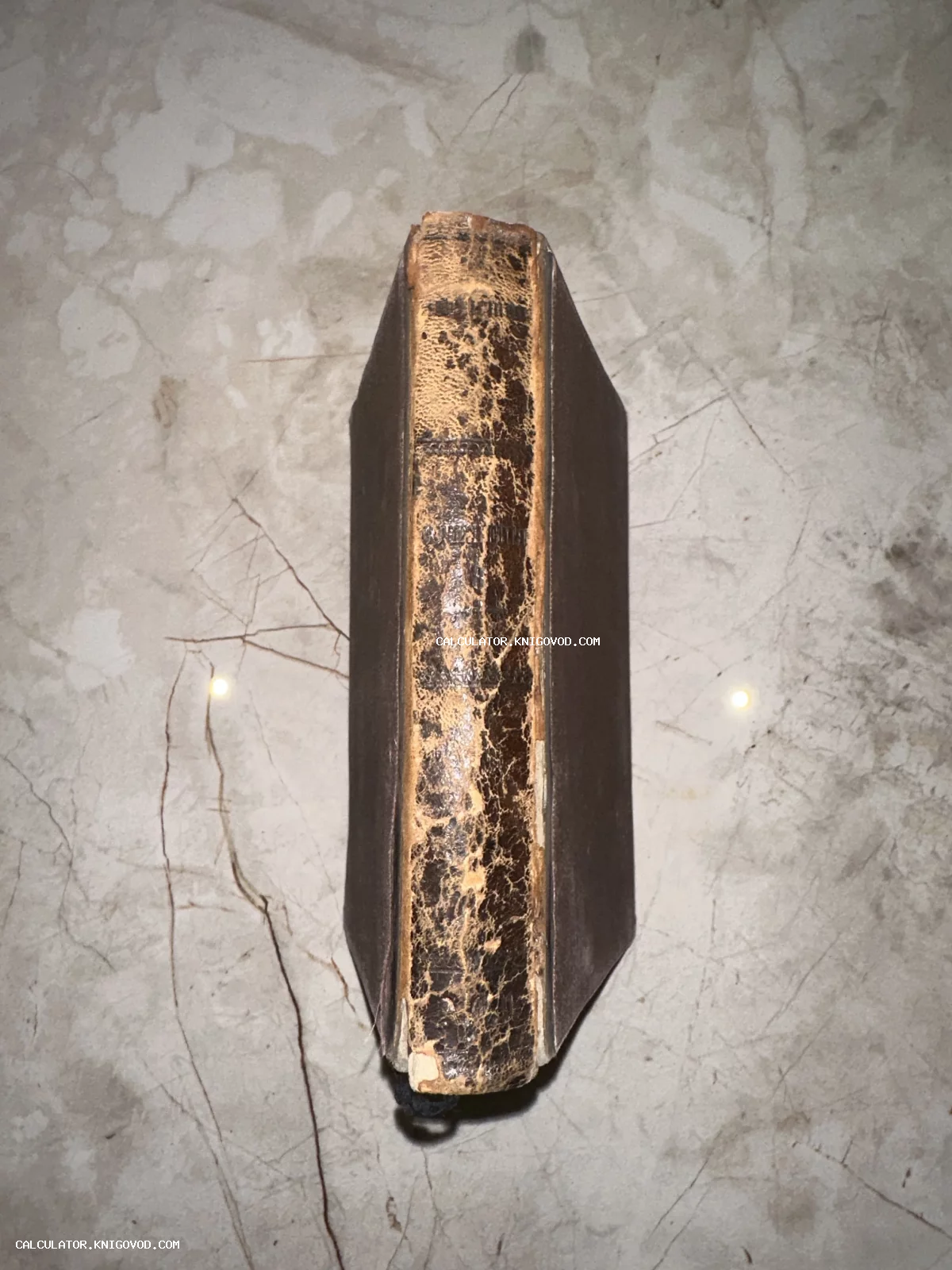 Вид сверху на сильно потертый кожаный корешок старинной книги с трещинами и следами времени.