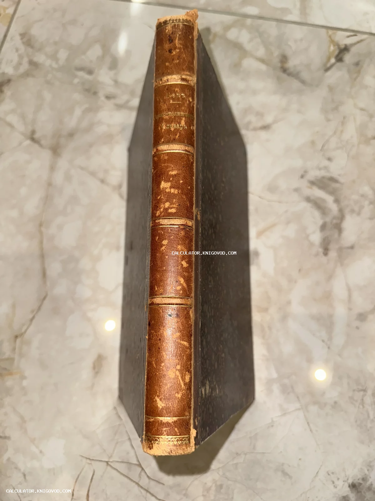 Кожаный корешок старинной книги с золотым тиснением 'Юридическо-политический словарь' на мраморном фоне.