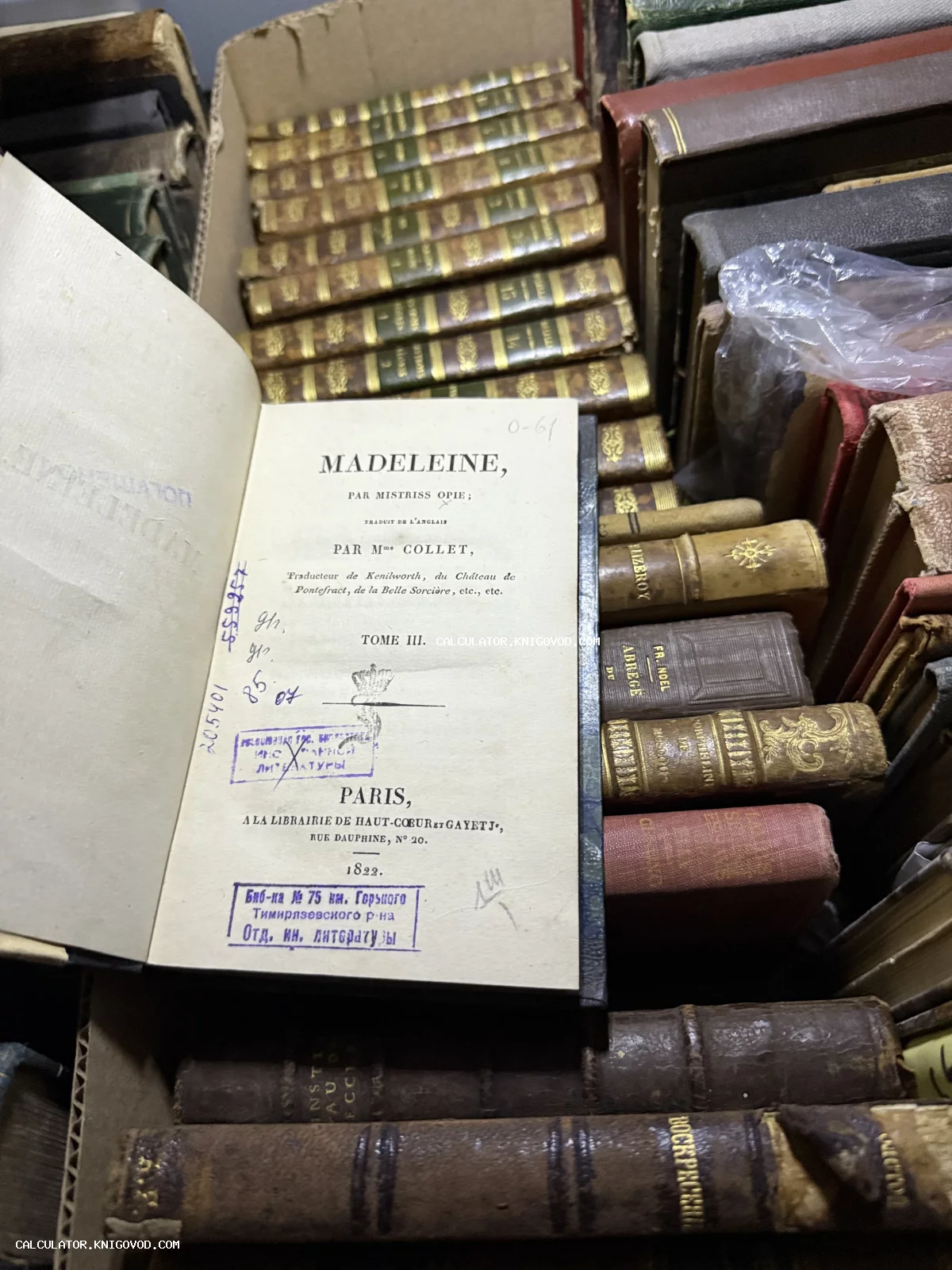 Разворот старинной книги 1822 года с названием Madeleine на фоне множества антикварных томов в кожаных переплетах.