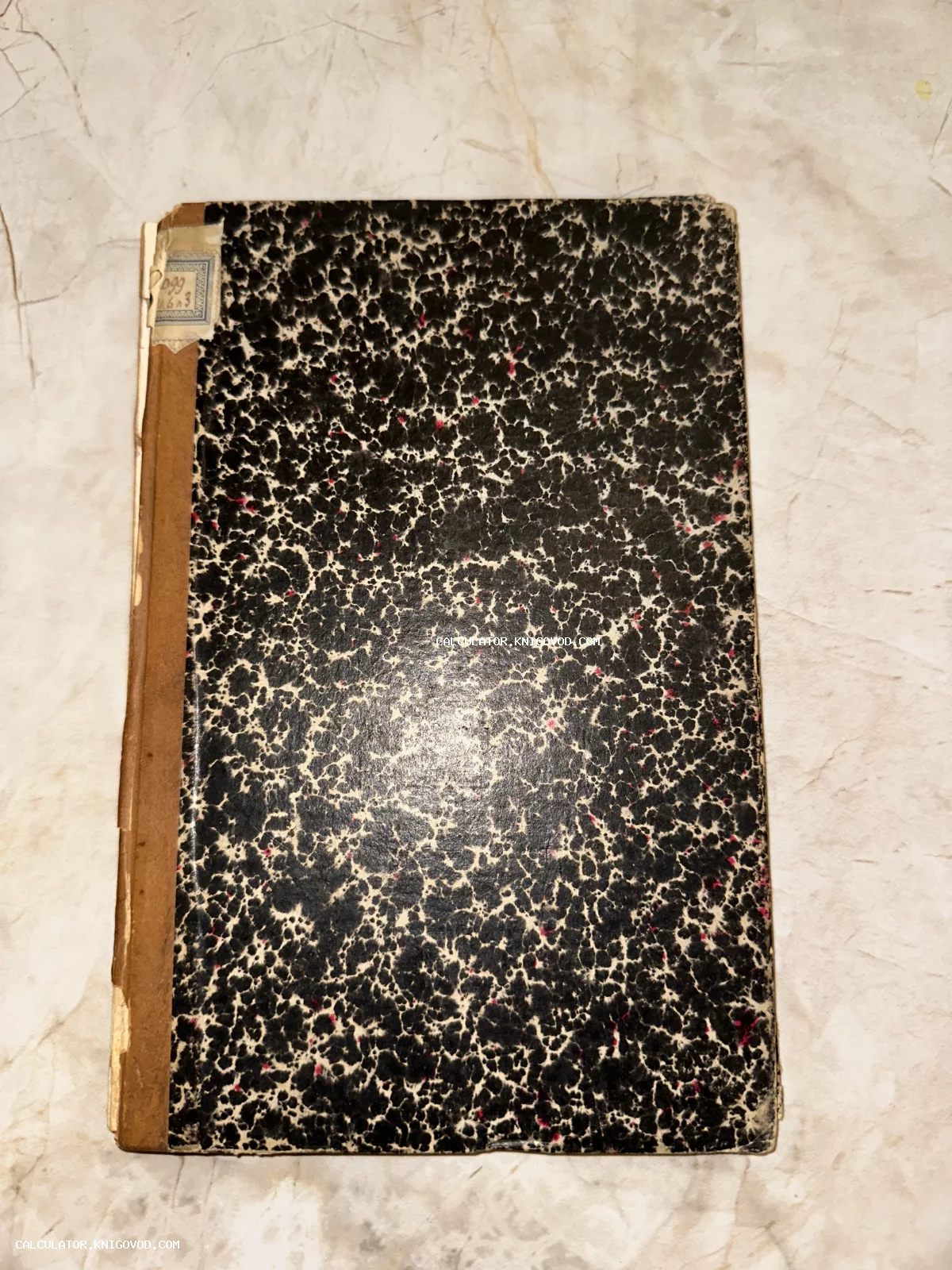 Обложка антикварной книги с черно-белым пятнистым узором и коричневым корешком.