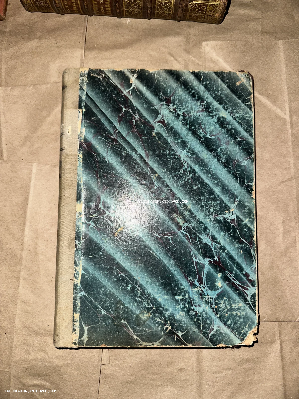 Антикварная книга с обложкой из мраморной бумаги бирюзового цвета с характерными потертостями на углах.