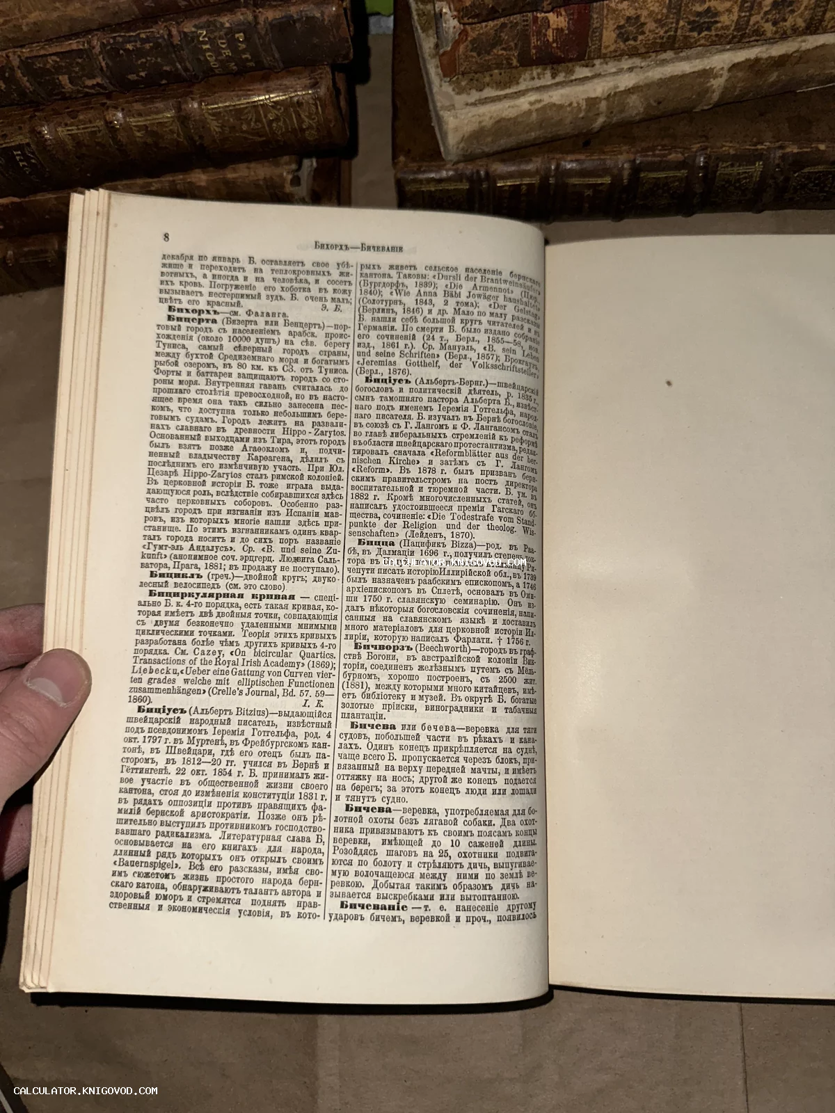 Открытая старинная книга с кириллическим текстом в дореволюционной орфографии на фоне других фолиантов.