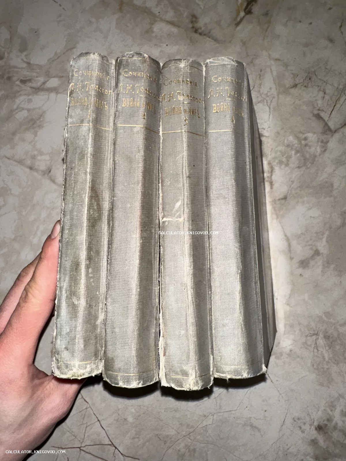 Четыре тома старинного издания романа Льва Толстого «Война и мир» в серых тканевых переплетах с золотым тиснением на корешках.