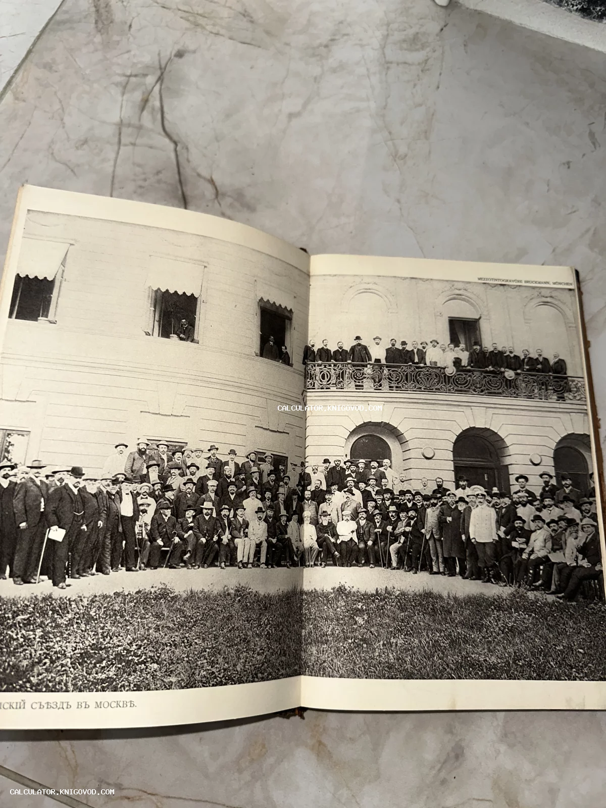Разворот старинной книги с черно-белой фотографией большой группы мужчин в костюмах и шляпах конца XIX века перед фасадом здания в Москве.
