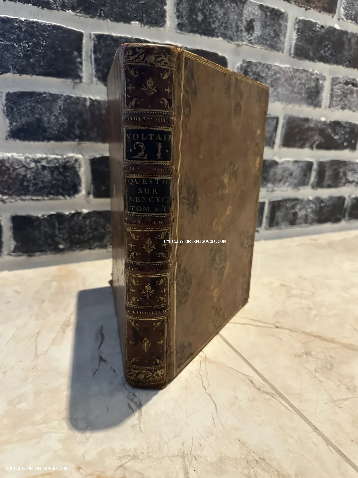 Старинная книга Вольтера в кожаном переплете с золотым тиснением на корешке, первый том «Вопросов к Энциклопедии».