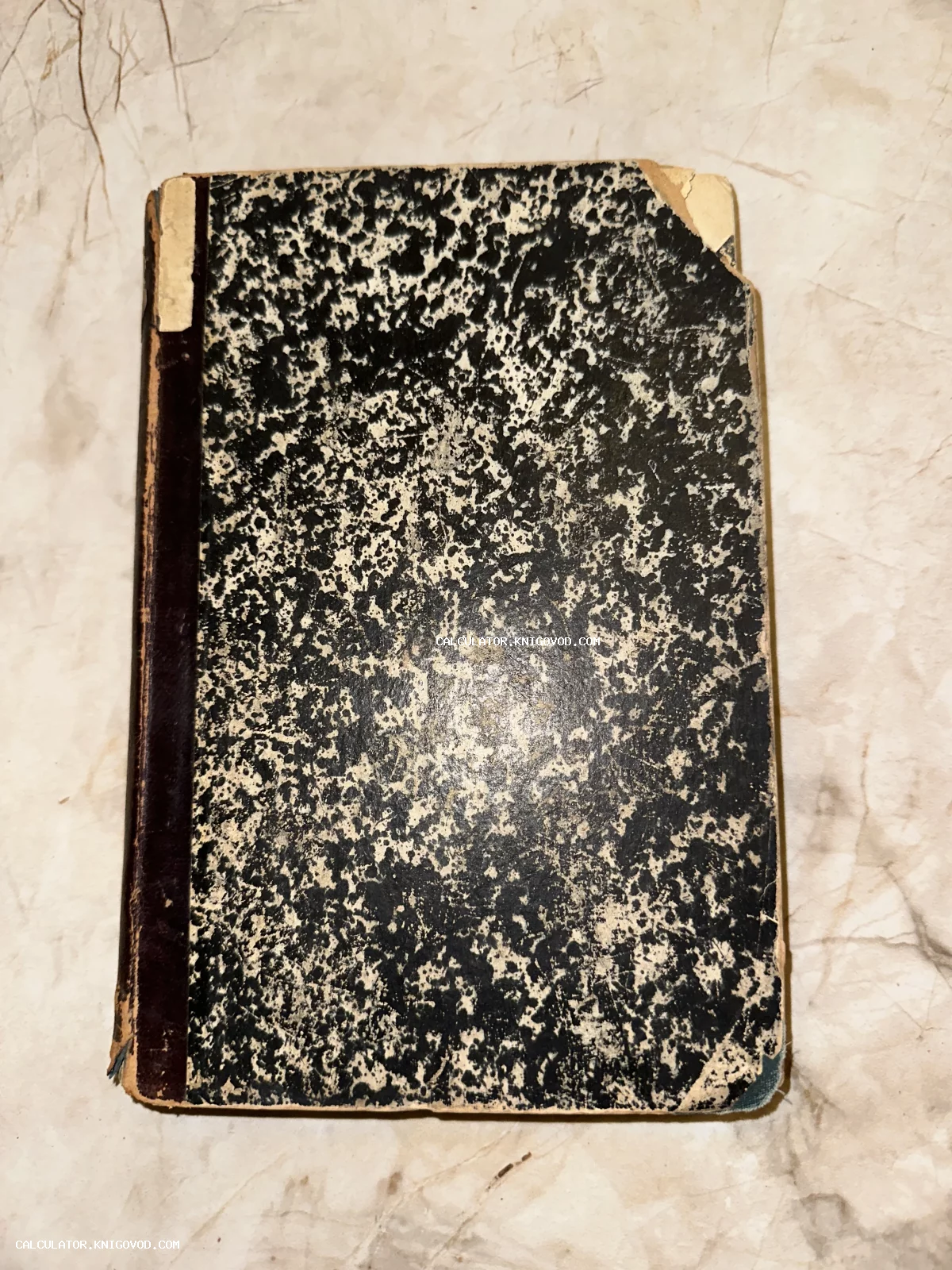 Обложка старинной книги с черно-белым мраморным узором и потертым кожаным корешком на светлом фоне.