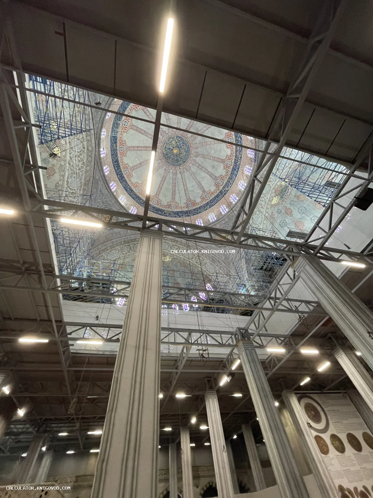 Интерьер мечети с массивными колоннами и расписным куполом в процессе реставрации со строительными лесами.