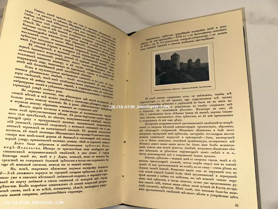 Разворот антикварной книги с текстом на дореволюционном русском языке и черно-белой фотографией крепости в Каменце-Подольском.