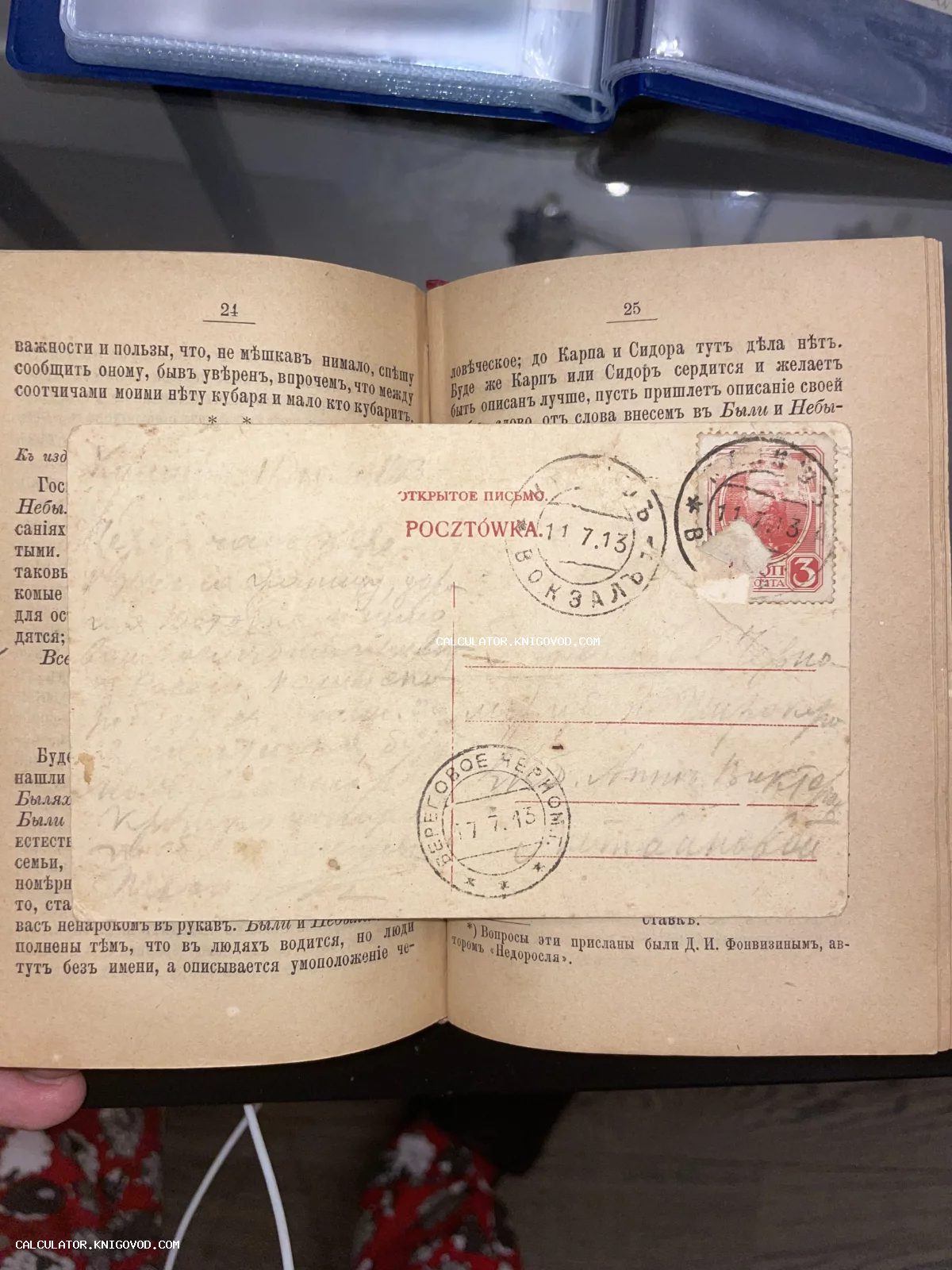 Антикварная почтовая открытка с маркой и штемпелями 1913 года, лежащая на развороте старой книги с дореволюционным шрифтом.