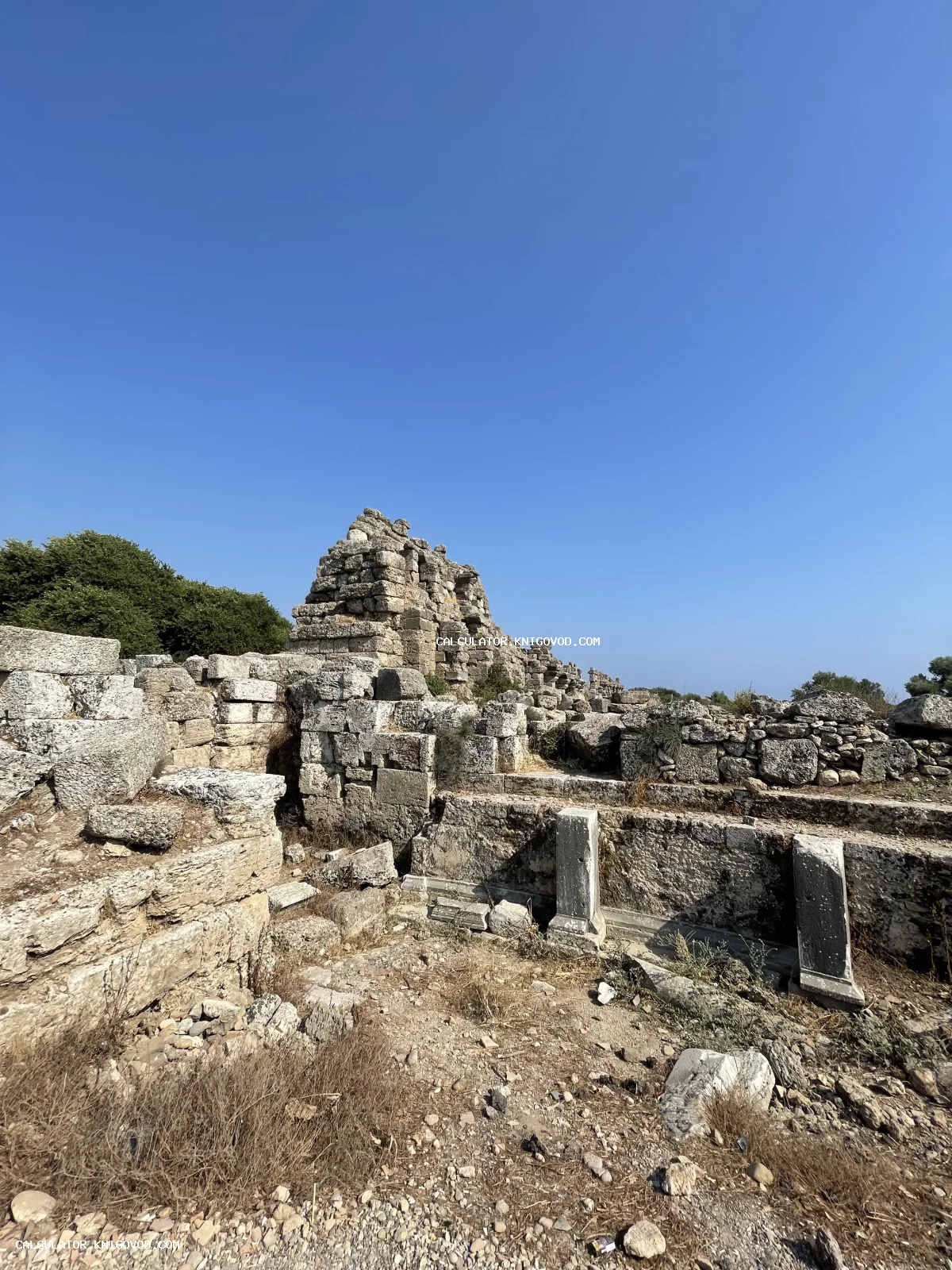 Остатки древних каменных стен и фундаментов под ясным синим небом.