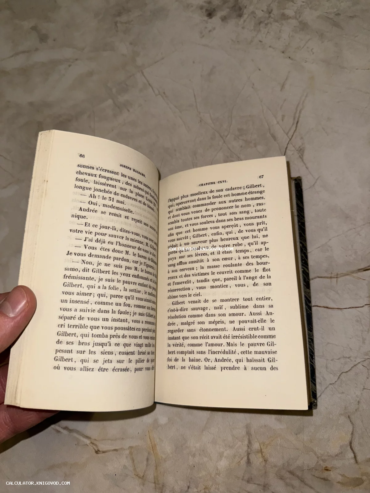 Разворот старинной книги на французском языке с текстом романа Жозеф Бальзамо на фоне мраморного стола.