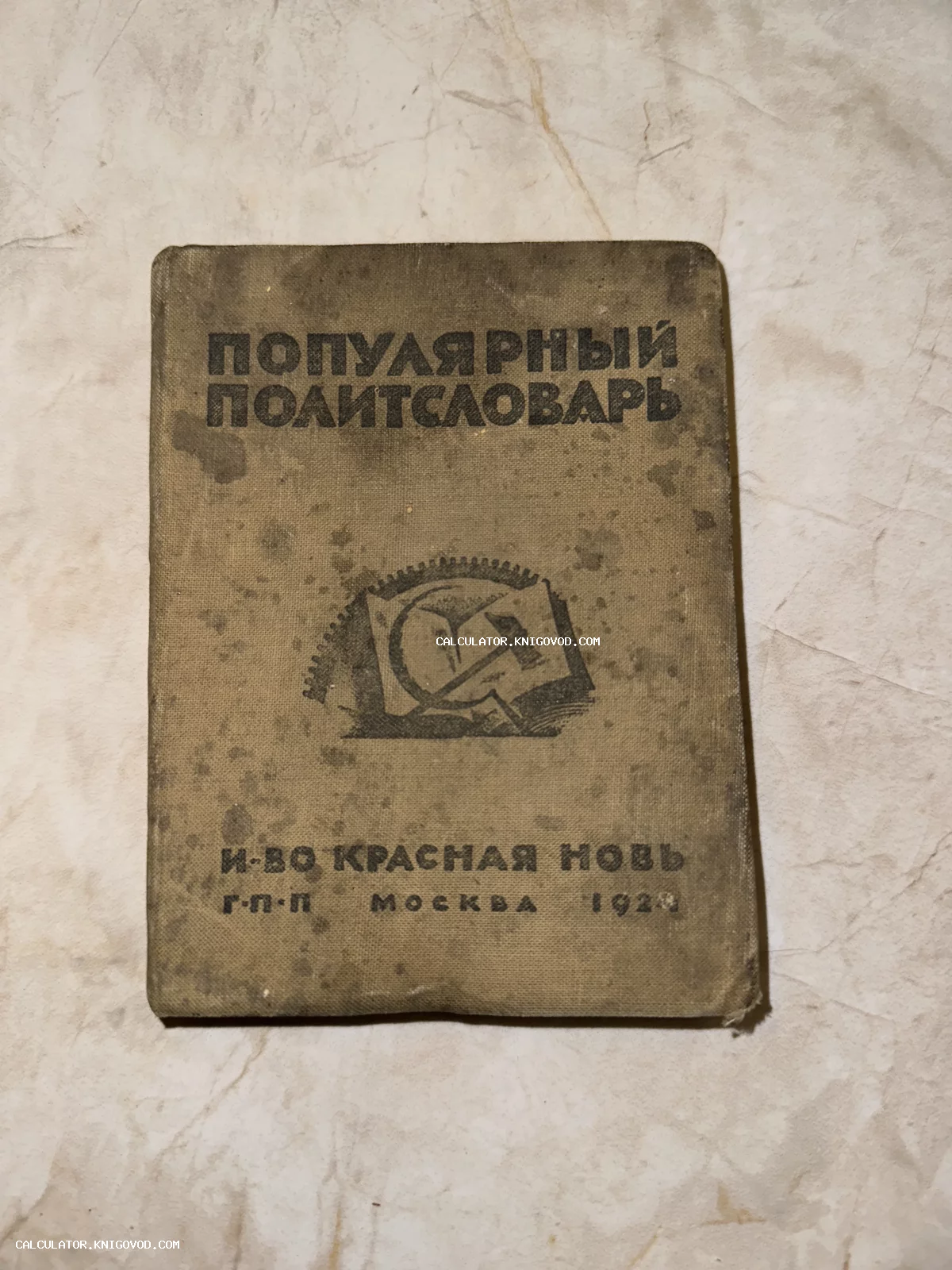 Старинная книга в тканевом переплете с надписью Популярный политсловарь и эмблемой серпа и молота на фоне шестерни.