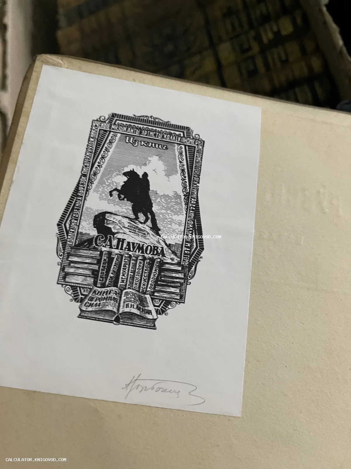 Графический оттиск экслибриса с изображением памятника Петру I, книжных полок и цитаты о силе книг на светлом фоне.