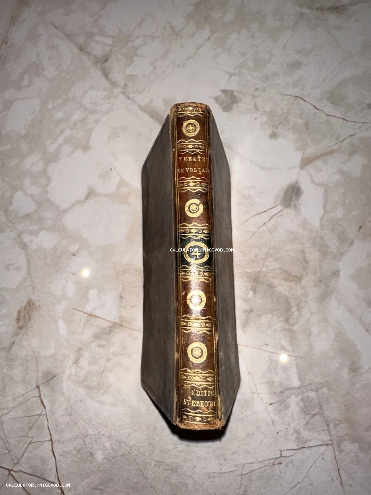 Корешок антикварной книги в кожаном переплете с золотым тиснением 'Theatre de Voltaire', четвертый том.