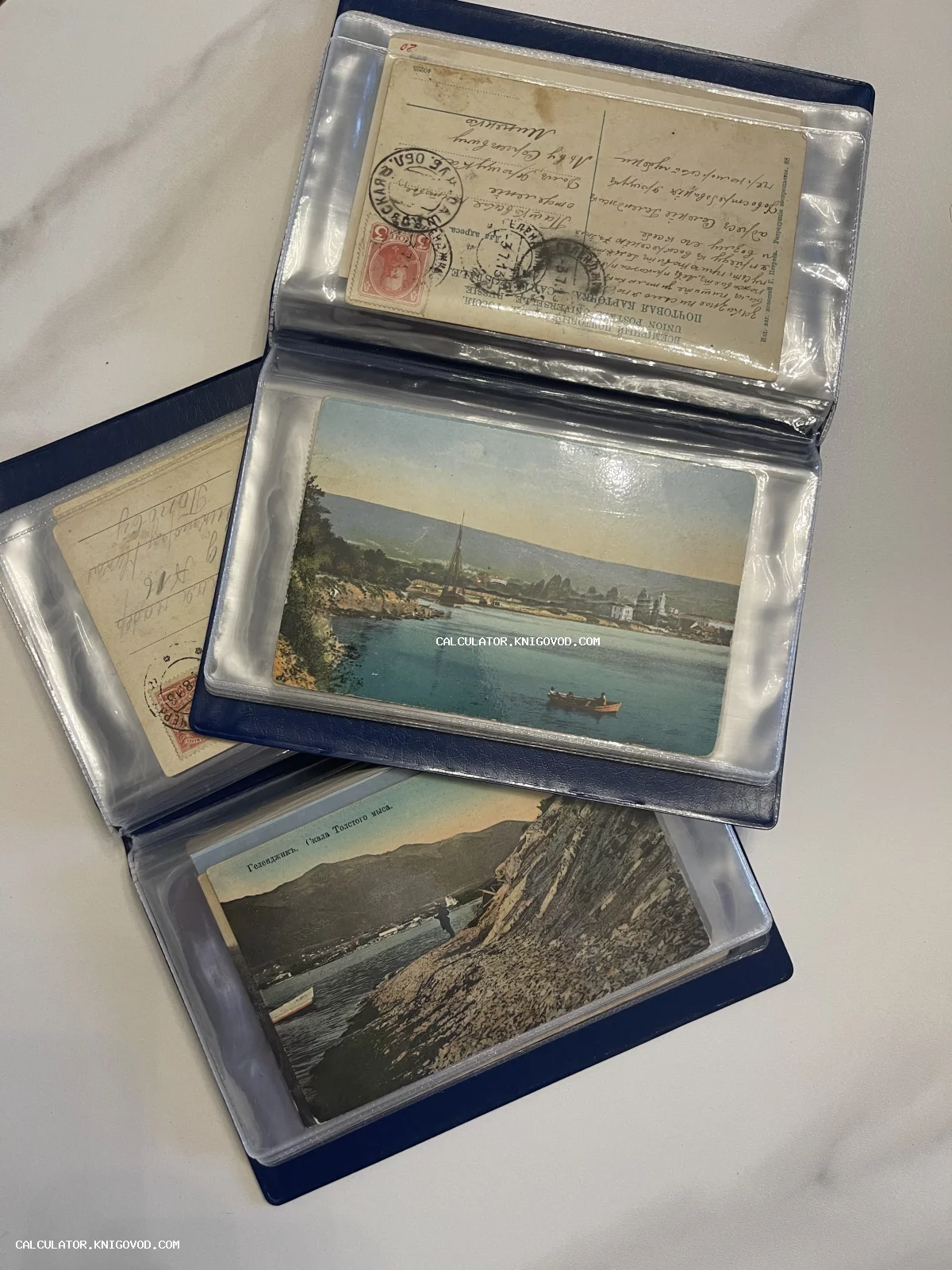 Старинные почтовые открытки в синем альбоме, изображающие виды Геленджика и оборотную сторону с письмом и марками 1913 года.