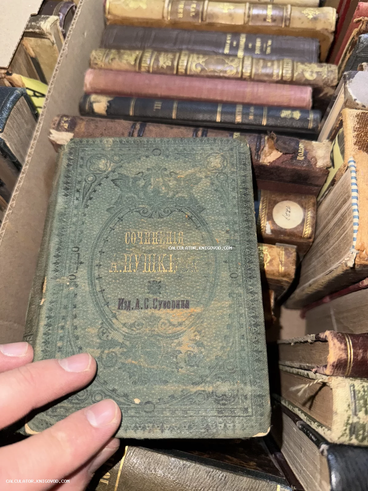 Старинная книга в зеленом тканевом переплете с золотым тиснением «Сочинения А. Пушкина», издание А. С. Суворина, в коробке с другими антикварными книгами.