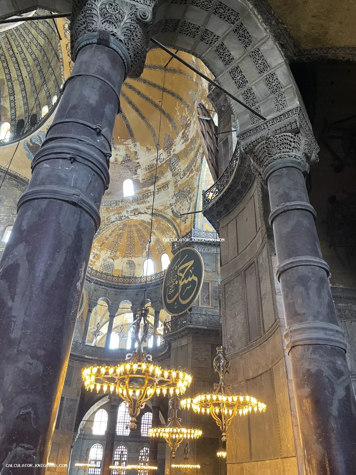 Внутренний вид собора Святой Софии в Стамбуле: массивные мраморные колонны, золоченые люстры и византийские своды с арабской каллиграфией.
