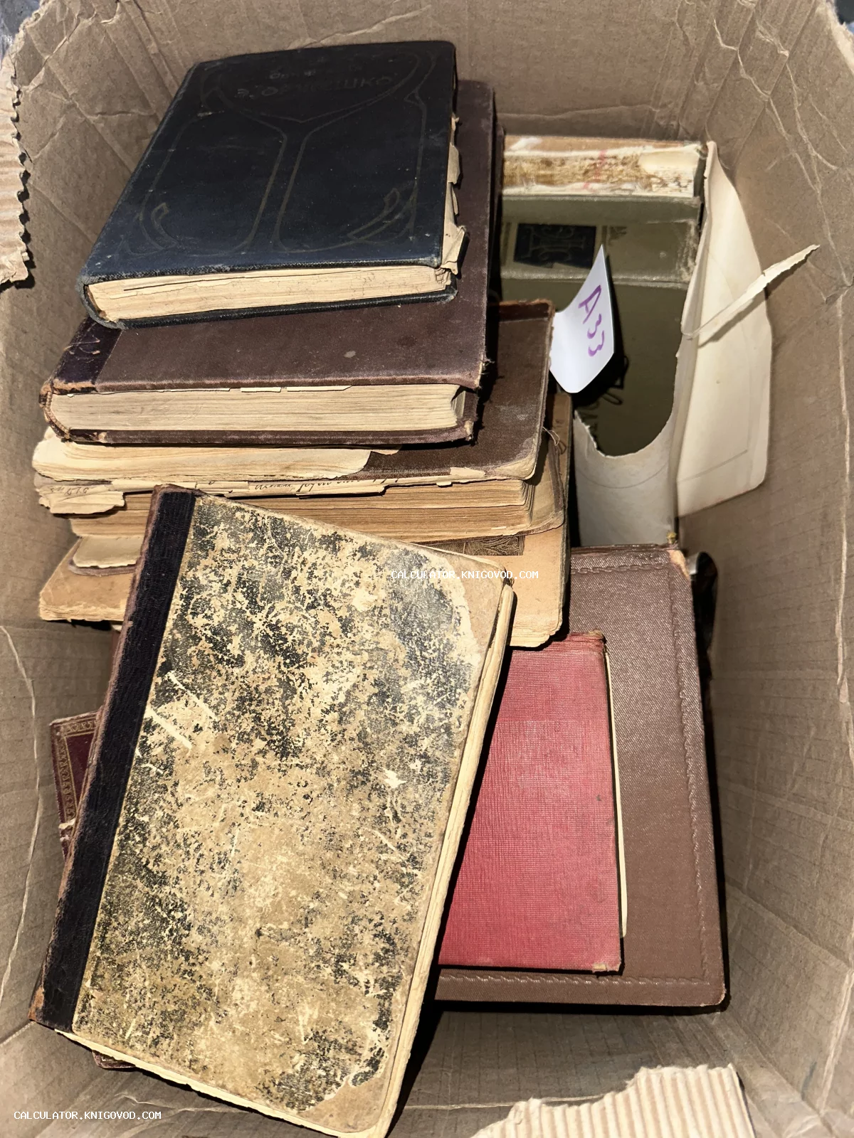 Множество старых книг с потертыми обложками и пожелтевшими страницами в картонной коробке.