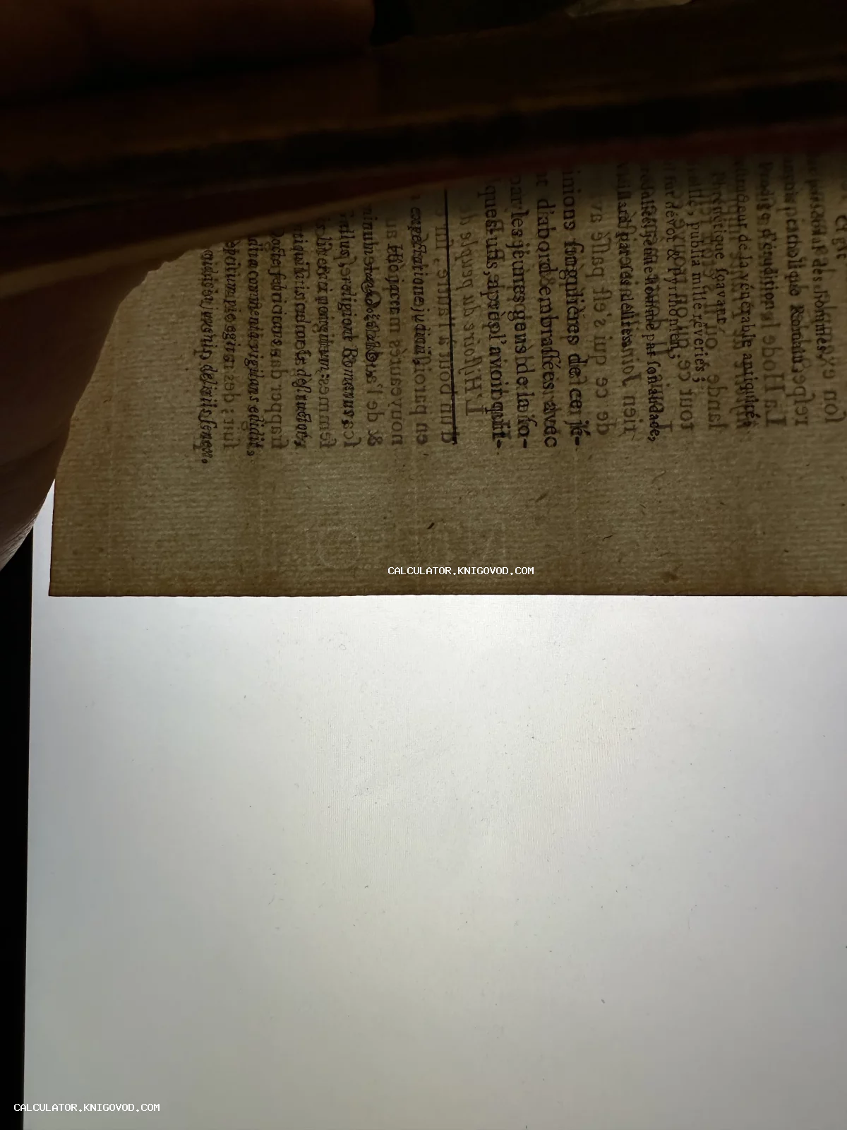 Крупный план страницы старинной книги с латинским и французским текстом, снятой на просвет.