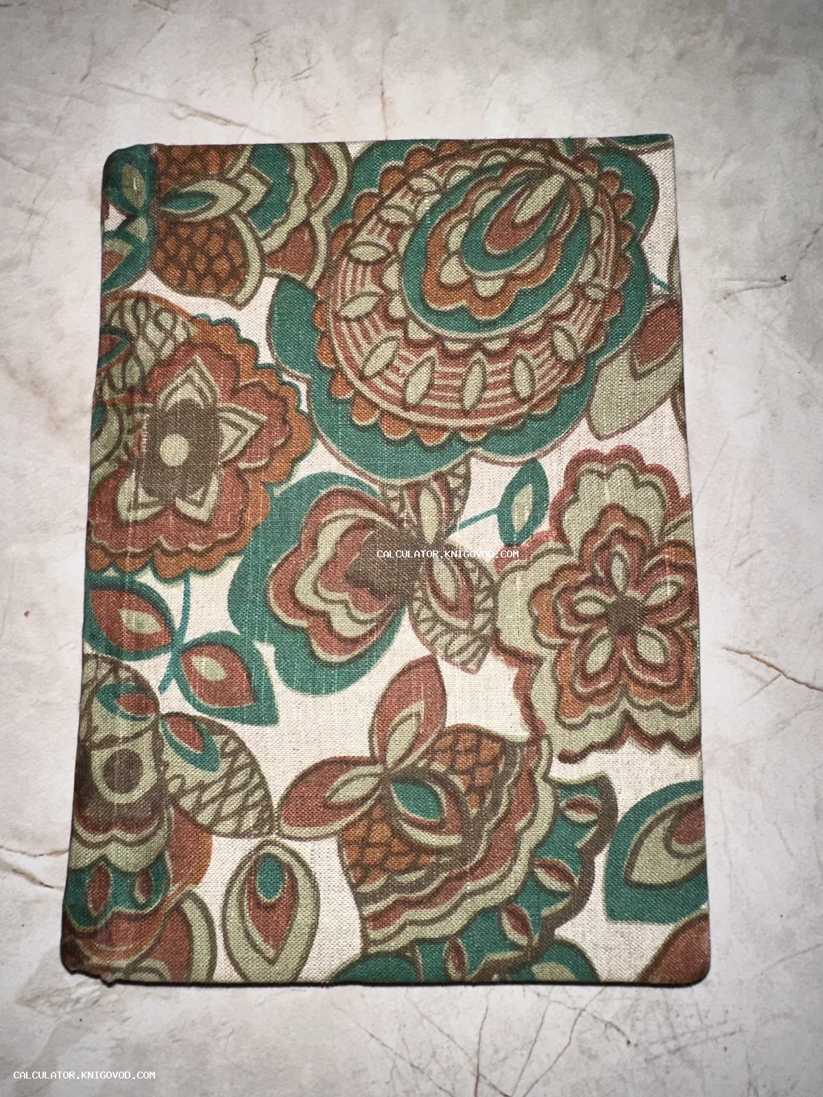 Книга в плотной тканевой обложке с крупным растительным узором в зеленых и коричневых тонах.