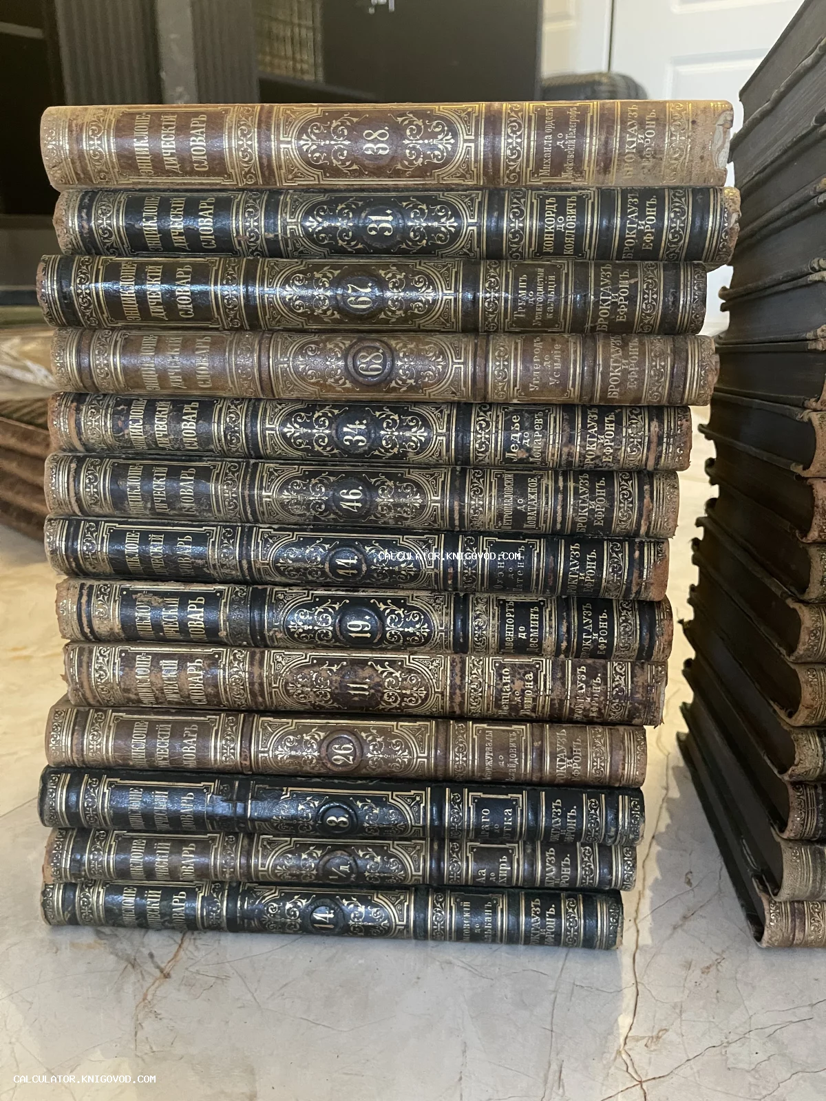 Стопка антикварных томов Энциклопедического словаря Брокгауза и Ефрона с золотым тиснением на кожаных корешках.